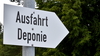 Zu sehen ist ein Schild in Form eines Pfeils auf dem "Ausfahrt Deponie" zu lesen ist. Der Pfeil zeigt nach links.