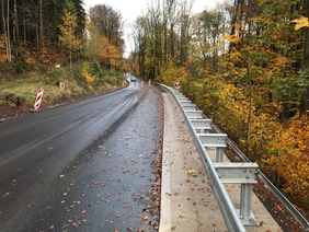 Zu sehen ist eine Straße an einem Waldgebiet.