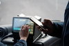 Zu sehen ist der Arm einer Person, die im Bus steht. In der Hand hält sie ein Handy in Richtung des  Cockpits des Busses. Dort drückt eine Person mit der Hand auf den Bildschirm eines Automaten. 