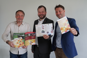 Der Bad Tabarzer Bürgermeister David Ortmann (von rechts), Landrat Onno Eckert und Kuramtsleiter Marcel Wedow stehen nebeneinander und halten Flyer für den Kreisseniorentag in den Händen.