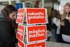 Ein Flyerständer. Darauf eine rote Postkarte mit den Worten "Zukunftsgestalter" und "Möglichmacher". 