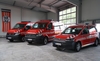 Zu sehen sind drei Feuerwehrfahrzeuge, die nebeneinander in einer Halle stehen.