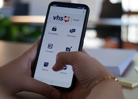 Zu sehen ist ein Handy im Großformat. Auf dem Bildschirm ist die Startseite der VHS-Cloud geöffenet.