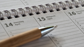 Eine Mülltonne steht vor einer Backstein-Hauswand. Auf dem Deckel ist eine mehrere Zentimeter hohe Schicht Schnee. Im Hintergrund sind zwei weitere Tonnen zu sehen.