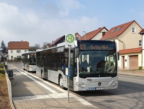 Auf dem Bild sind zwei graue Busse zu sehen. Die Busse stehen hintereinander an einer Haltestelle. Die Busse fahren auf der Line 810 und 820 nach Gotha Hbf