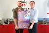Zwei Männer stehen nebeneinander. Sie halten zusammen ein Plakat in den Händen. Auf dem Plakat ist zu lesen: "Lass dich nicht K.O.-Tropfen".