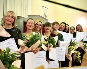 Zu sehen sind eine Gruppe Frauen. Sie stehen lächelnd nebeneinander und schauen in die Kamera. Alle halten einen Blumenstrauß und eine Urkunde in der Hand.