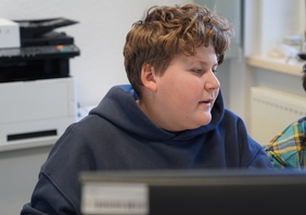 Zu sehen ist ein Junge, der an einem PC sitzt.