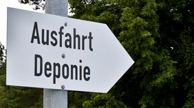 Zu sehen ist ein Schild in Form eines Pfeils auf dem "Ausfahrt Deponie" zu lesen ist. Der Pfeil zeigt nach links.