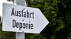 Zu sehen ist ein Schild in Form eines Pfeils auf dem "Ausfahrt Deponie" zu lesen ist. Der Pfeil zeigt nach links.