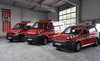Zu sehen sind drei Feuerwehrfahrzeuge, die nebeneinander in einer Halle stehen.